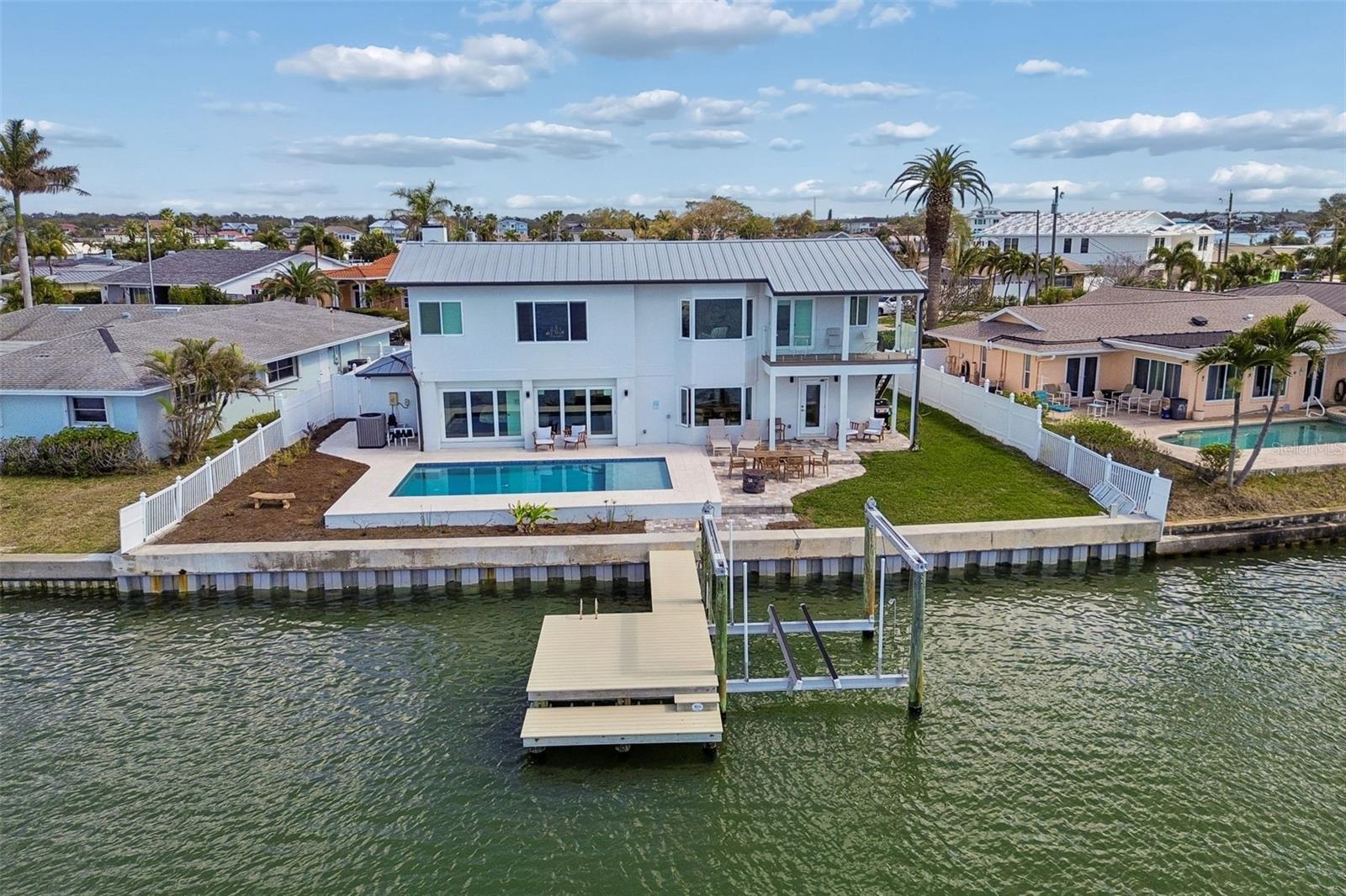 Two-story waterfront home with a backyard pool and private dock on a canal.