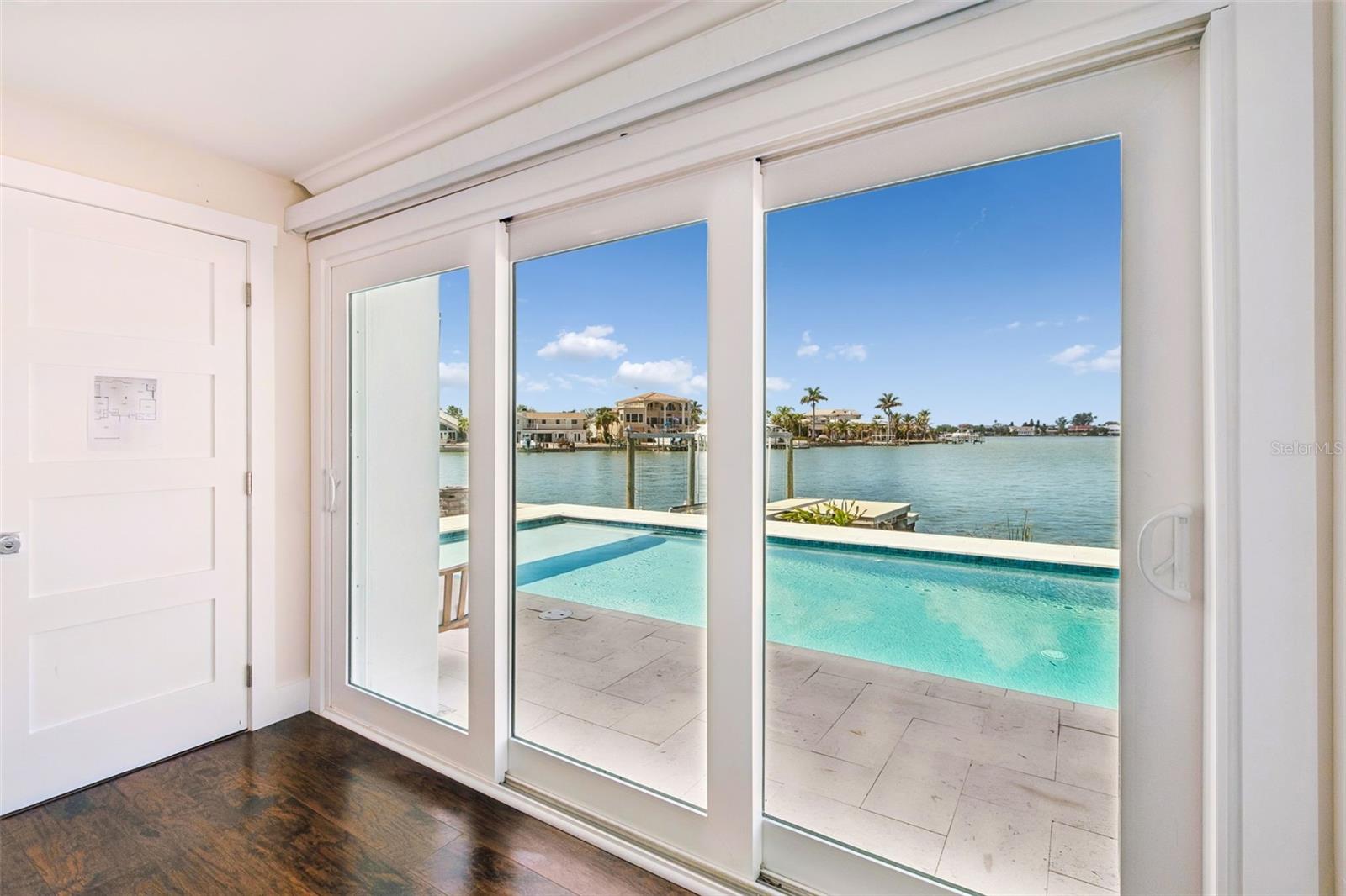 Sliding glass doors open to a pool and waterfront view.