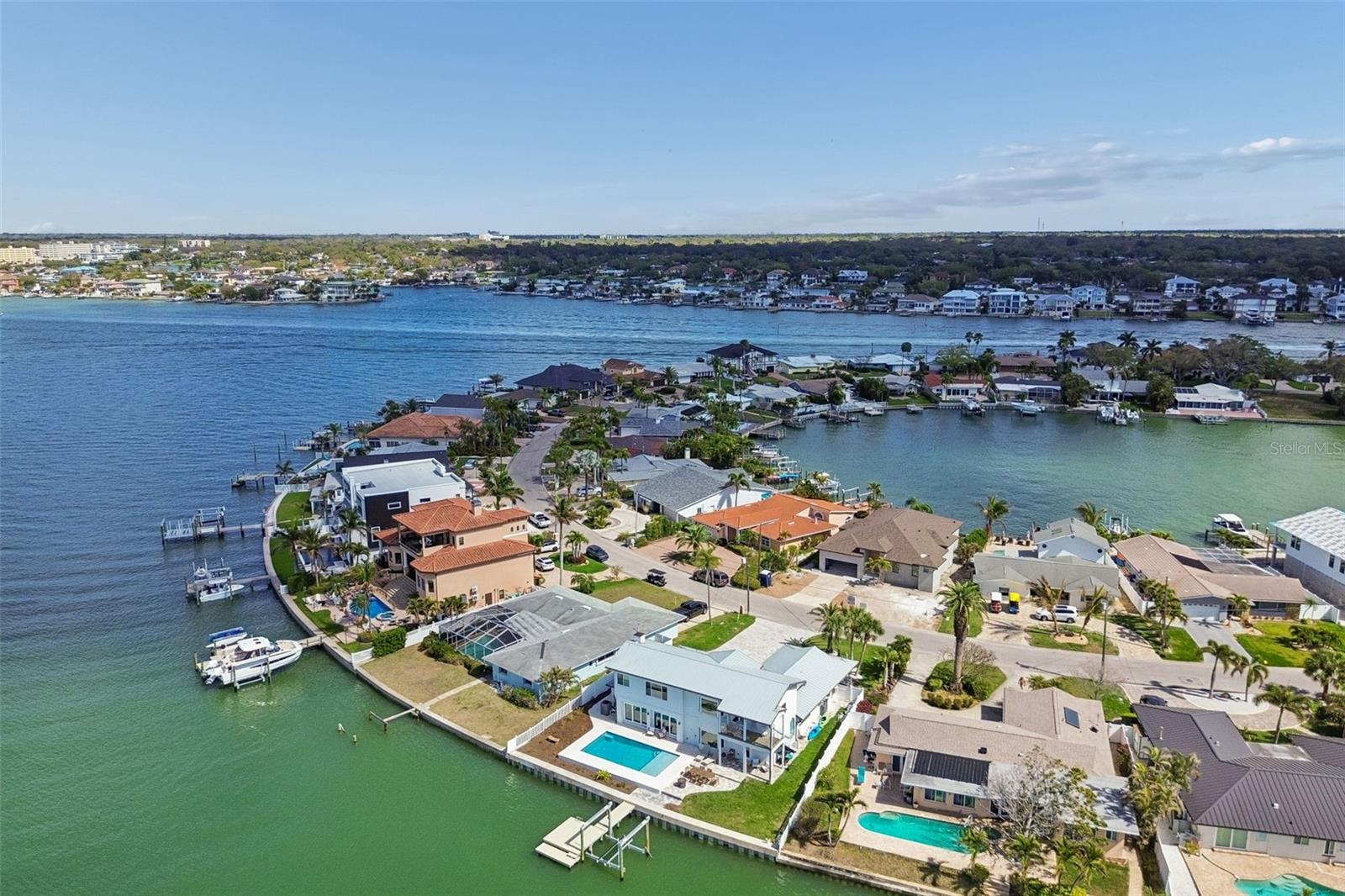 Aerial view of a waterfront home with a pool and dock beside a canal.