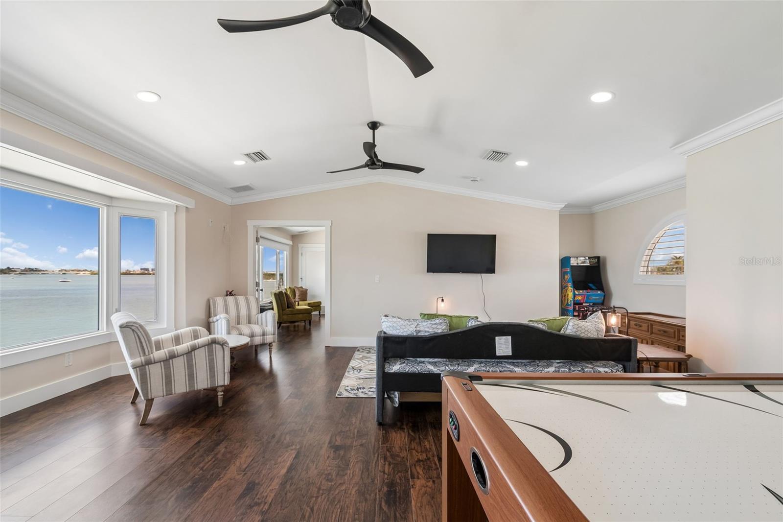 Furnished game room with a pool table and seating beside large windows overlooking the water.