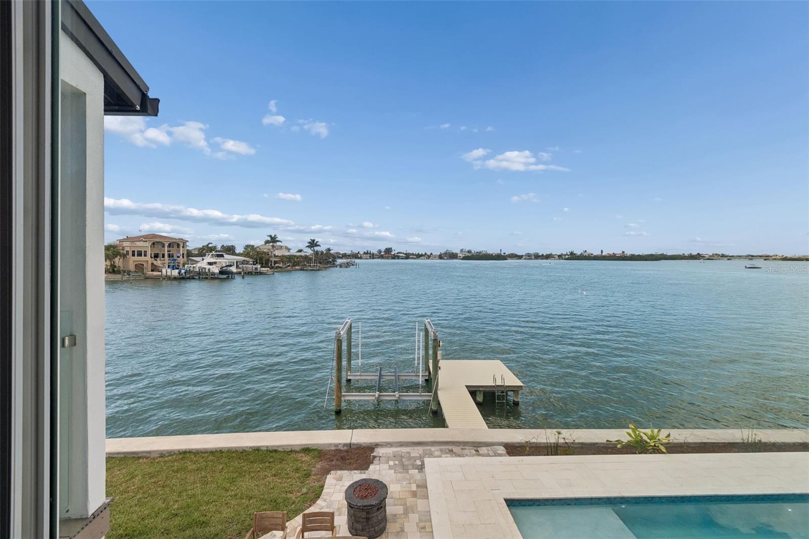 Bayfront view with a private dock, swimming pool, and neighboring homes across the water.