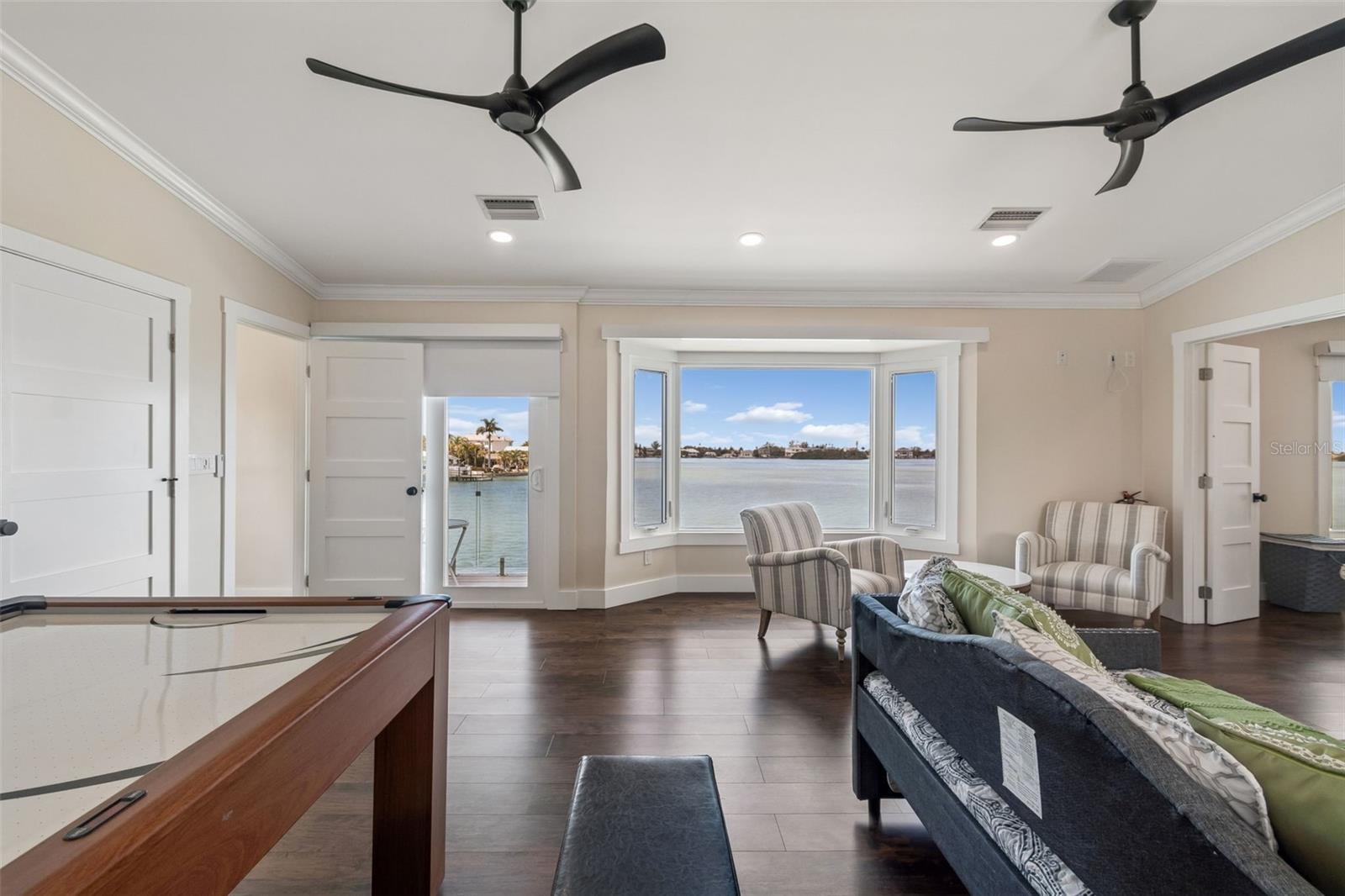 Furnished living room with a pool table and bay window overlooking the water.