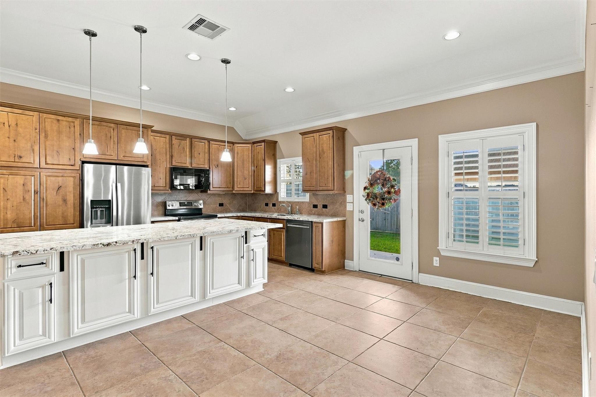 Kitchen with wood cabinets, a large white island, stainless steel appliances, and a glass back door.