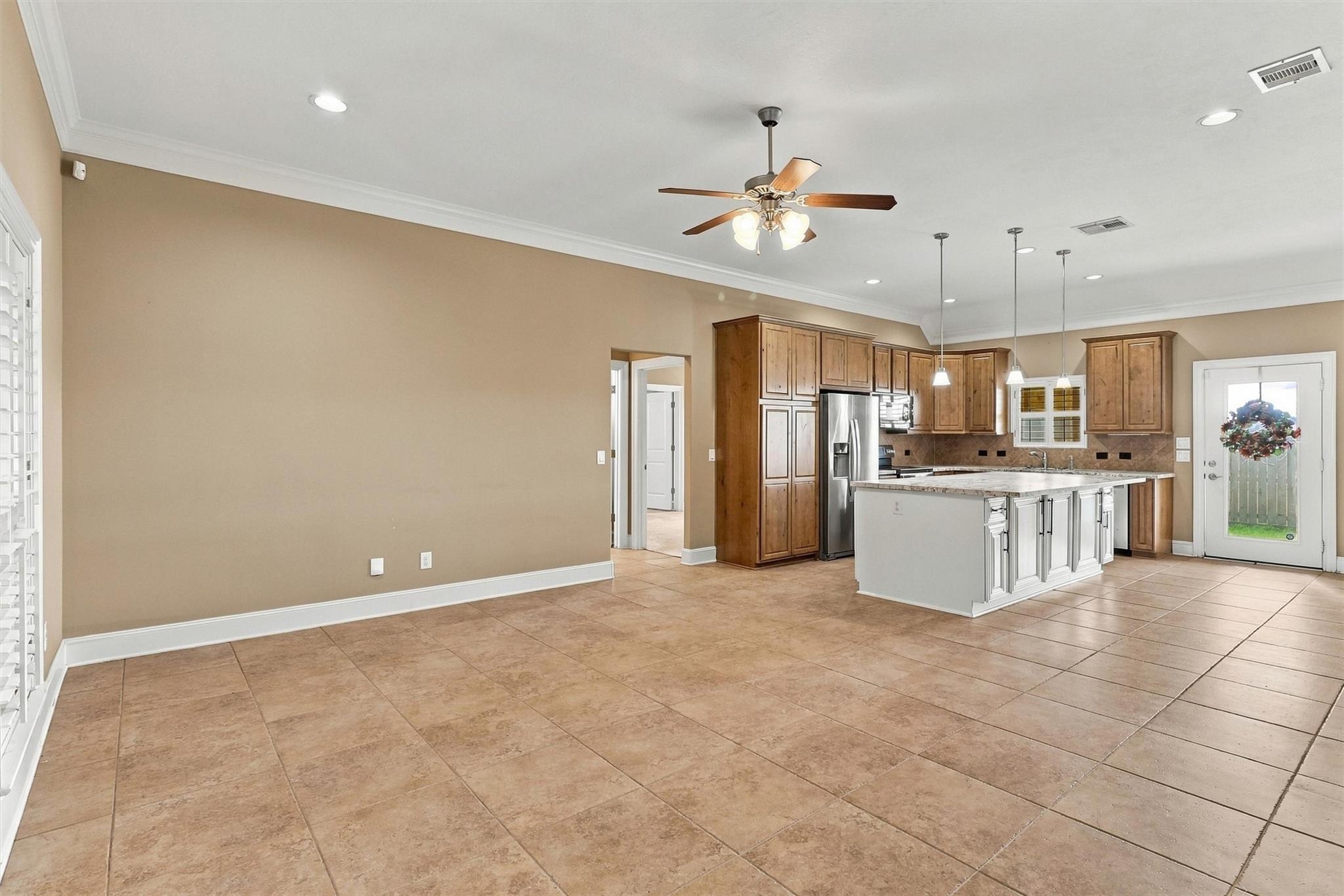 Open kitchen with wood cabinets, stainless steel appliances, and a large tiled floor.
