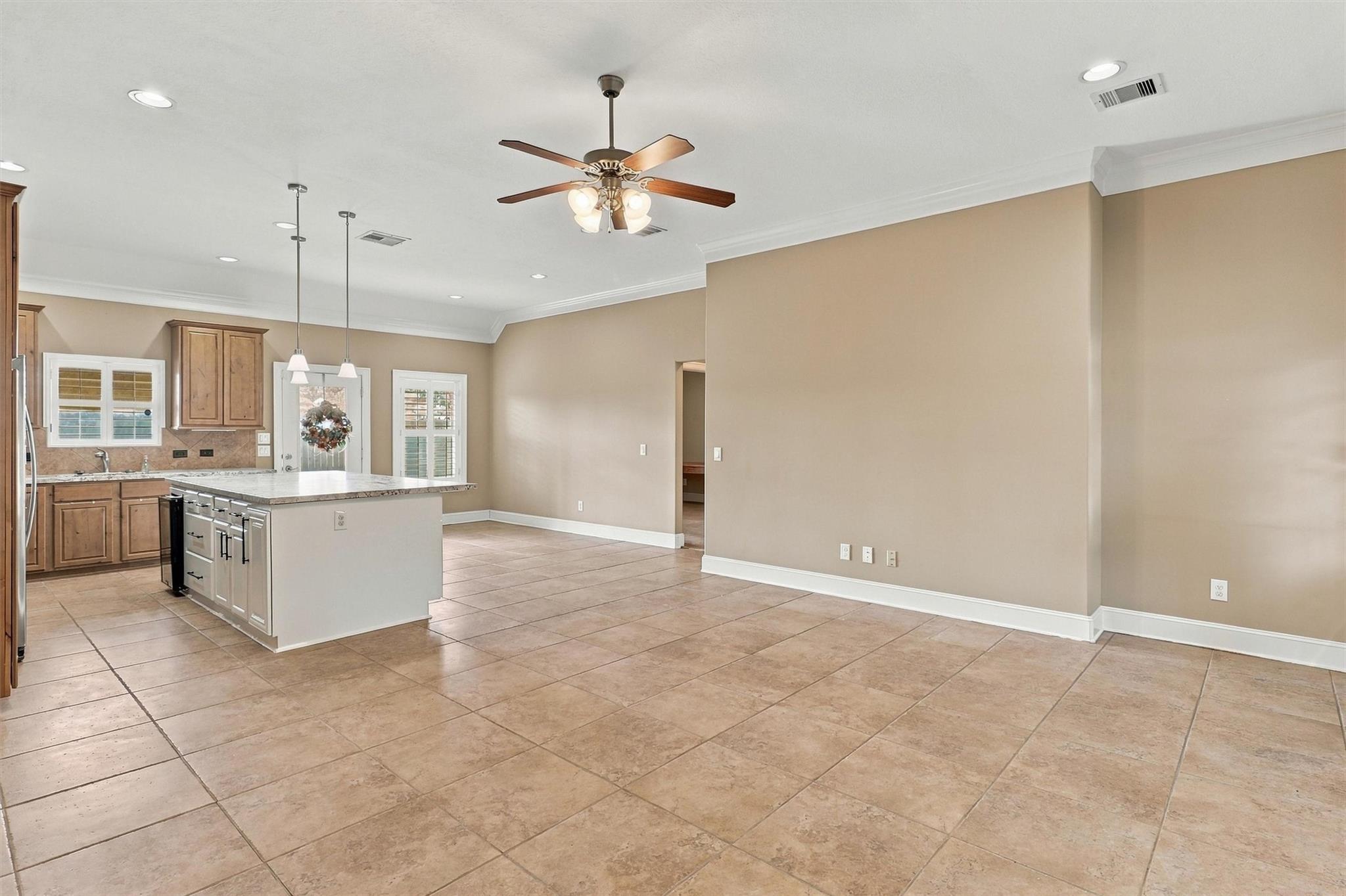 Open kitchen and dining area with a tiled floor, wood cabinets, and a light-colored island.