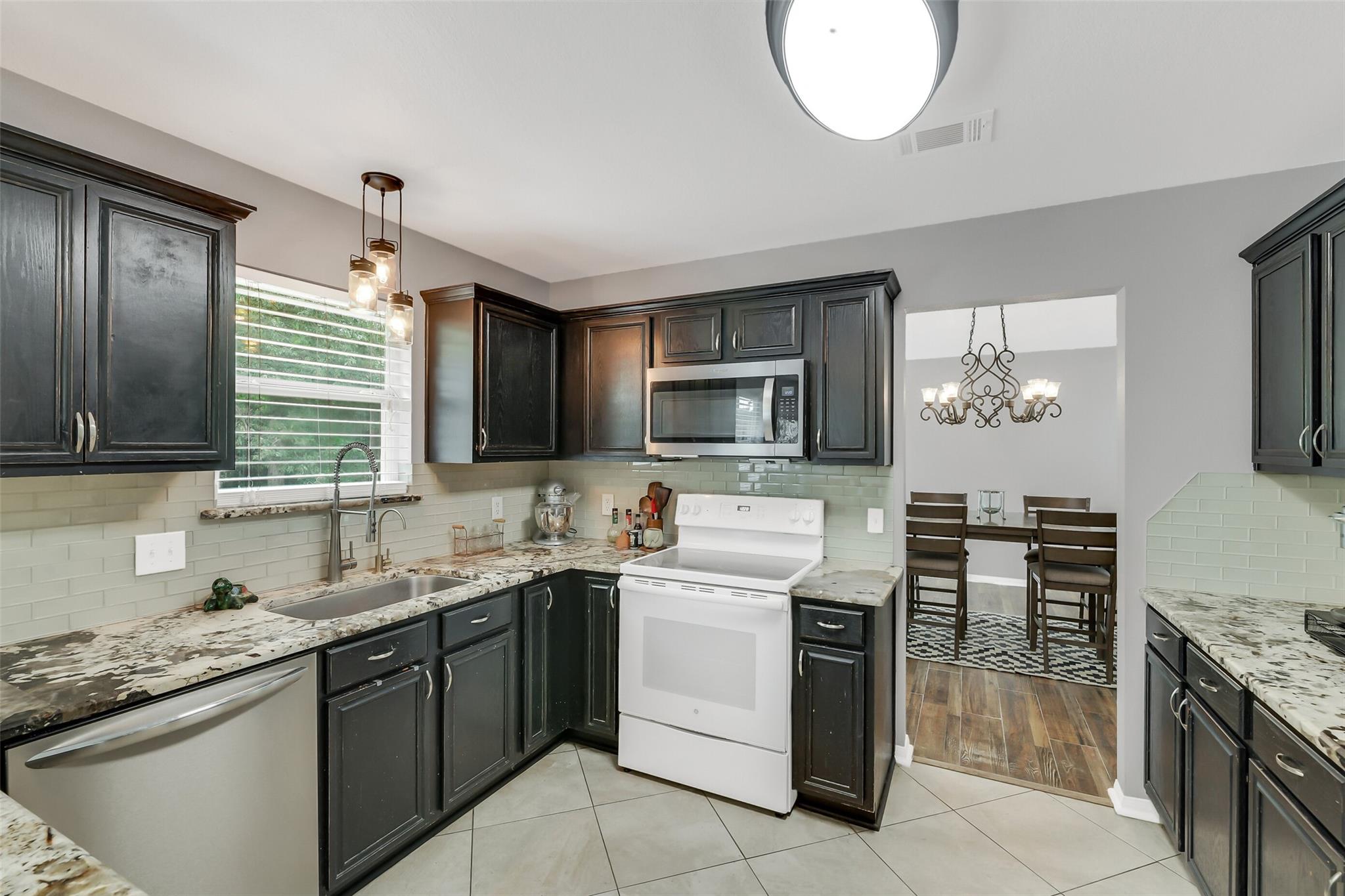 Kitchen with dark cabinets, granite counters, and a white range beside an opening to the dining area.