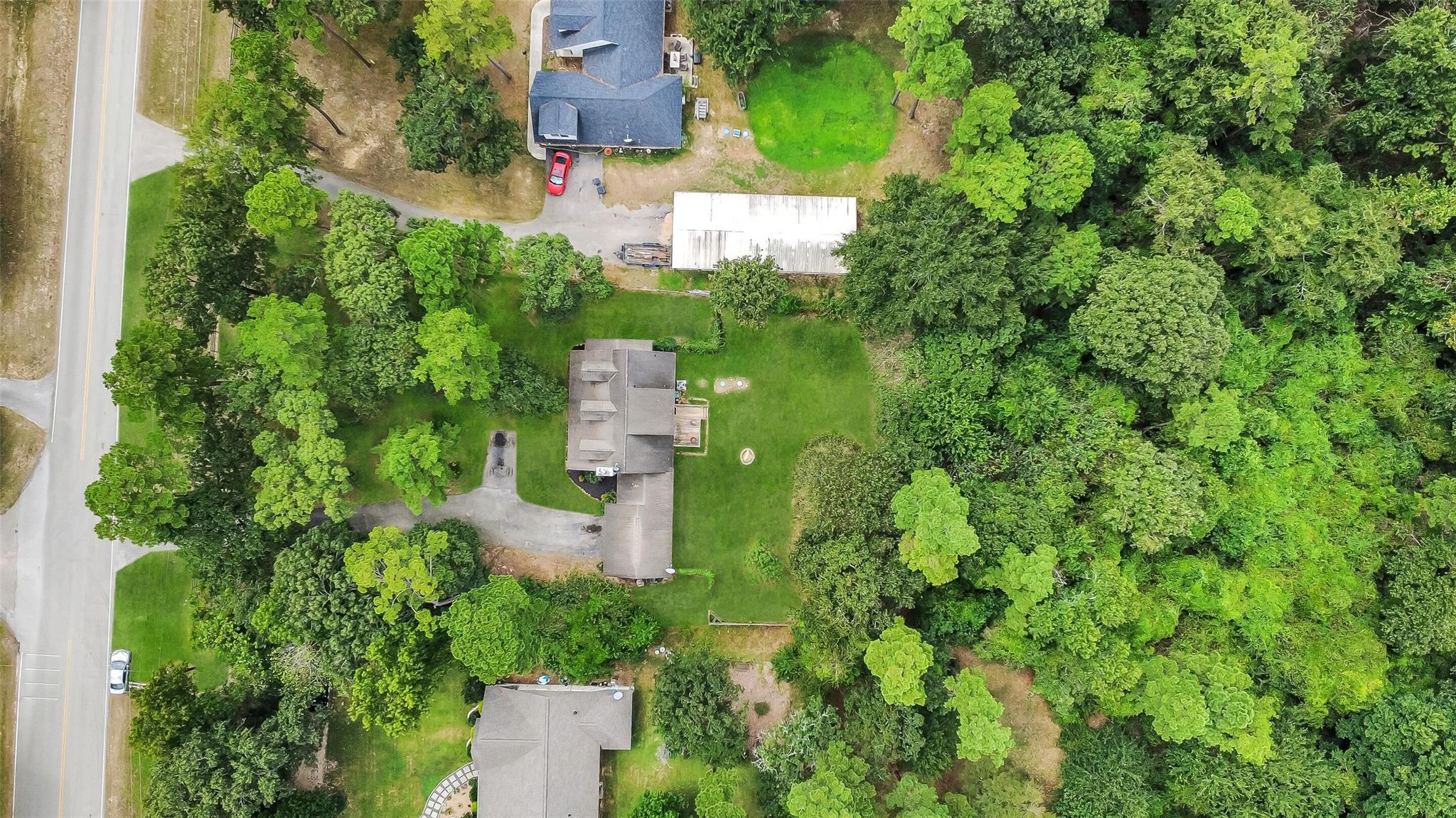 Aerial view of homes and green lawns surrounded by dense trees.