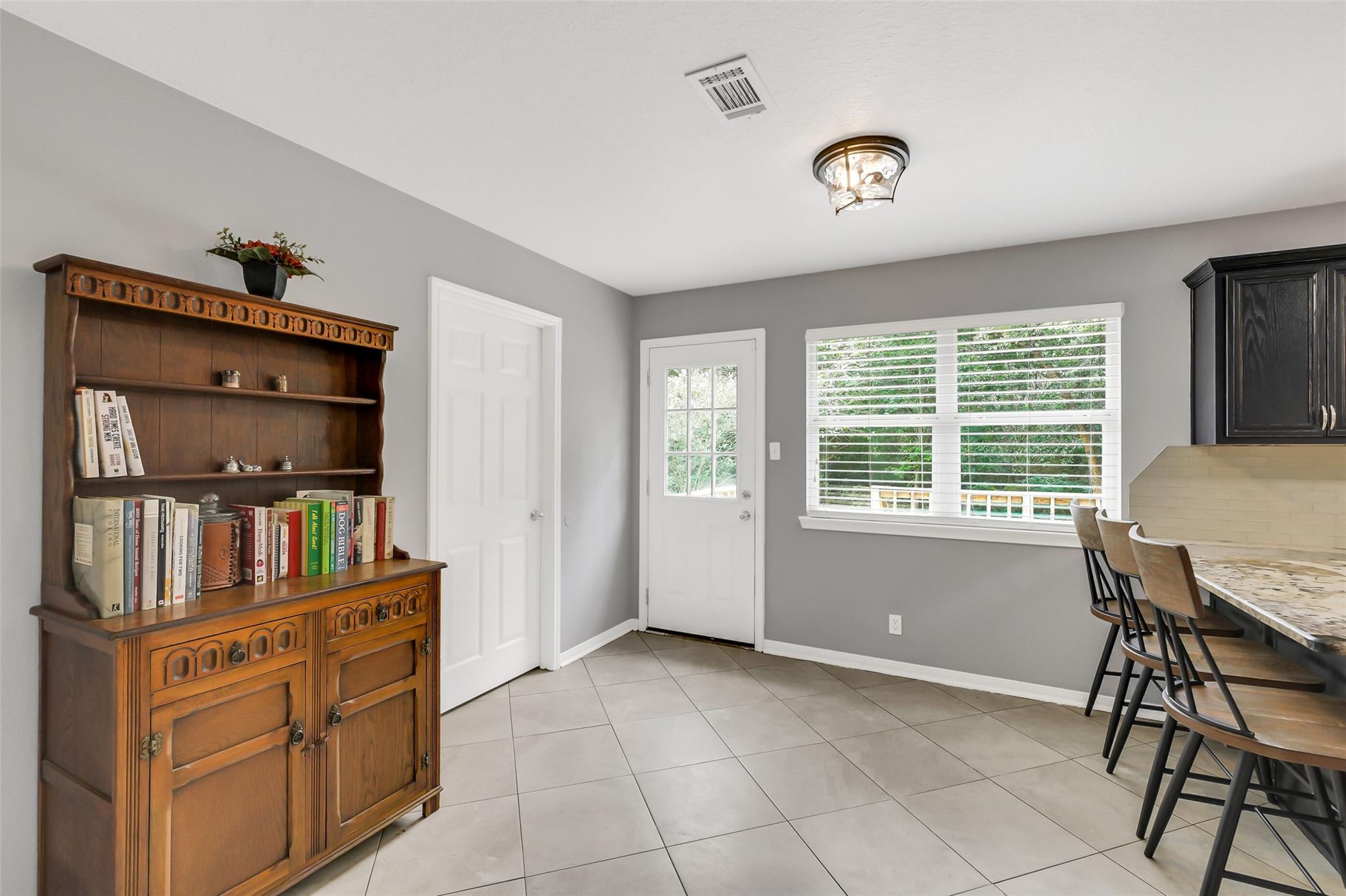 Kitchen with a granite breakfast bar, dark cabinets, and a carved wooden hutch beside a bright window.