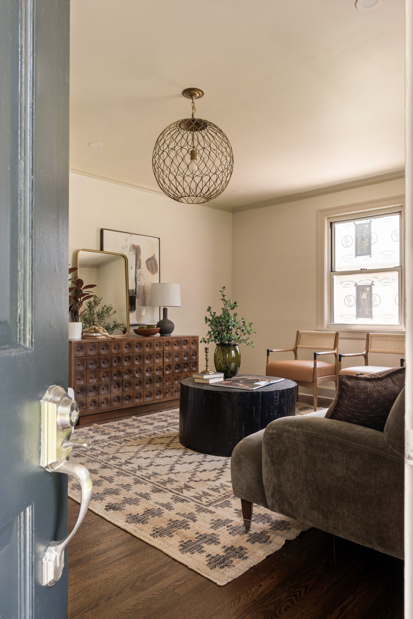Staged living room with a carved wood console, sculptural pendant light, and patterned rug.