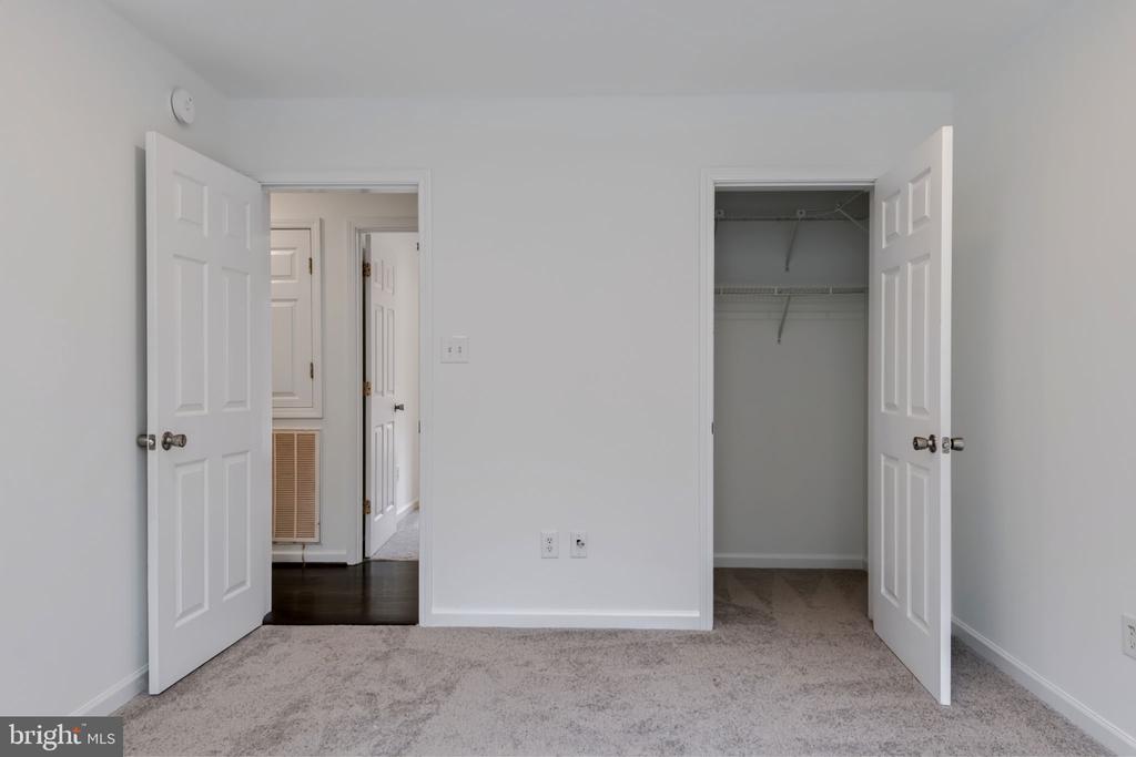 Empty bedroom with light carpet, an open closet, and double doors to the hallway.