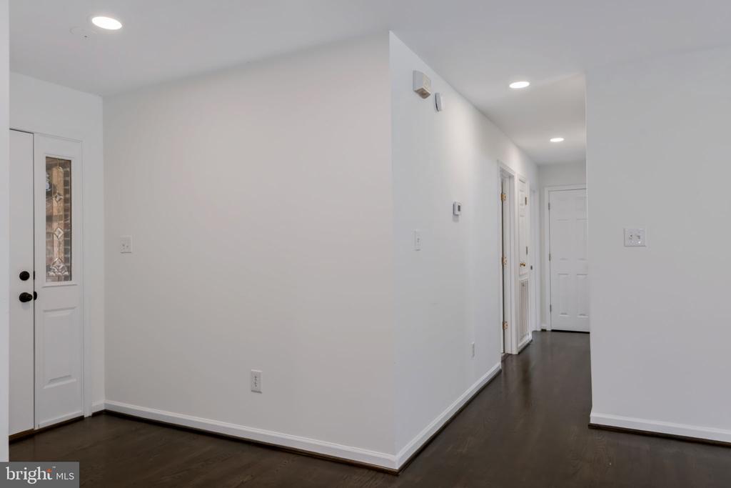 Entryway with dark hardwood floors and a front door with a decorative glass panel.