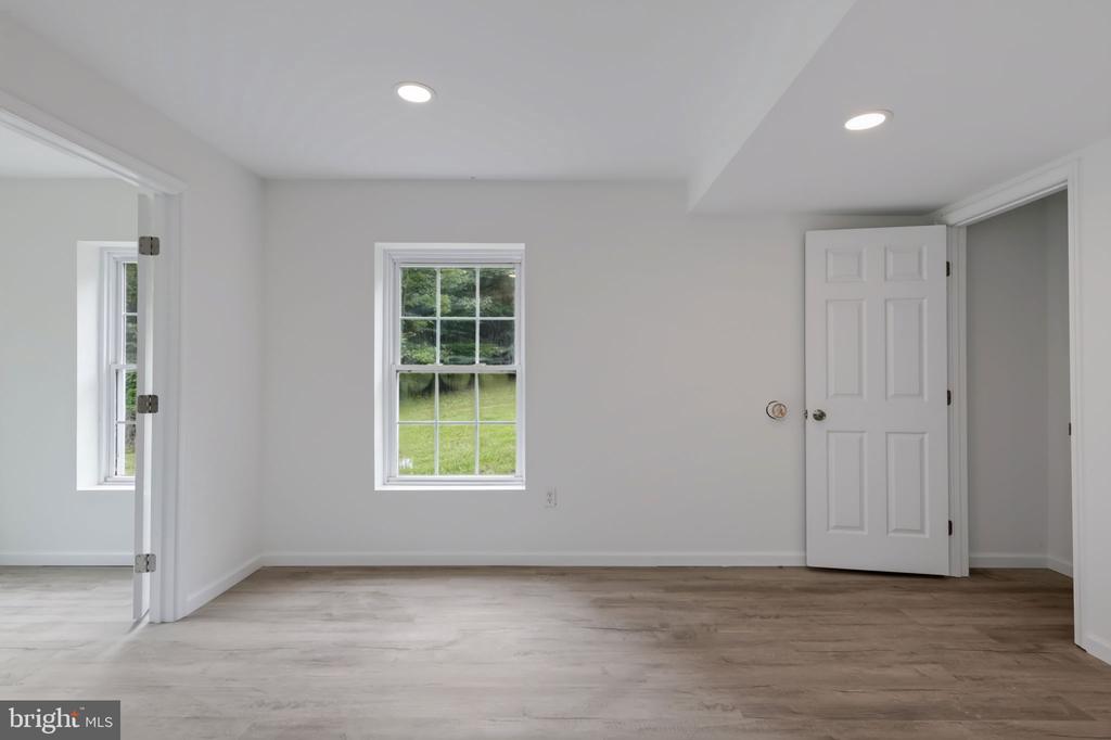Vacant room with light wood-look flooring, a window overlooking the lawn, and an open doorway.
