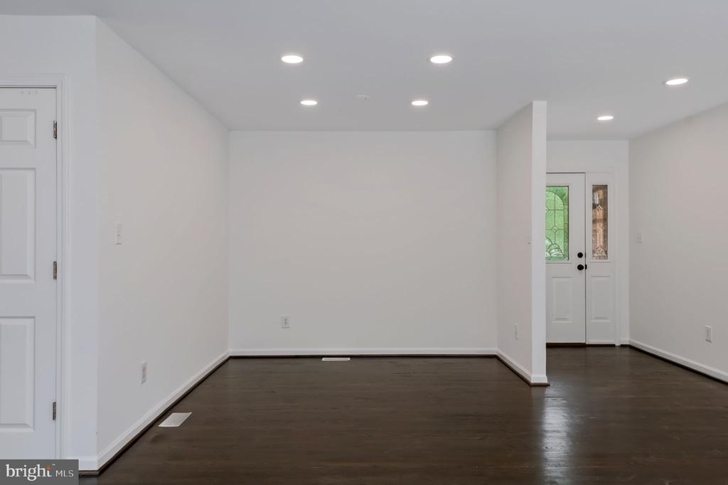 Vacant interior room with dark hardwood floors, recessed lighting, and a decorative-glass front door.