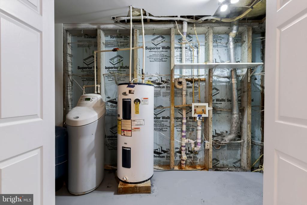 Unfinished utility room with two water heaters and exposed framing, insulation, pipes, and ductwork.