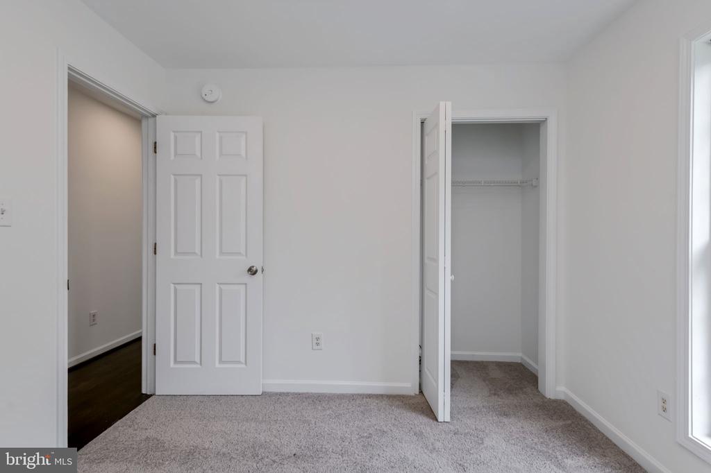 Vacant bedroom with gray carpet, an open closet, and a window.