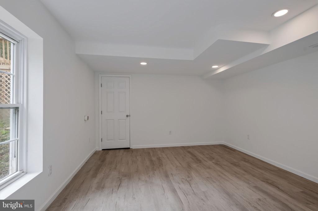 Empty finished room with light wood-look flooring, a large window, and recessed lights.
