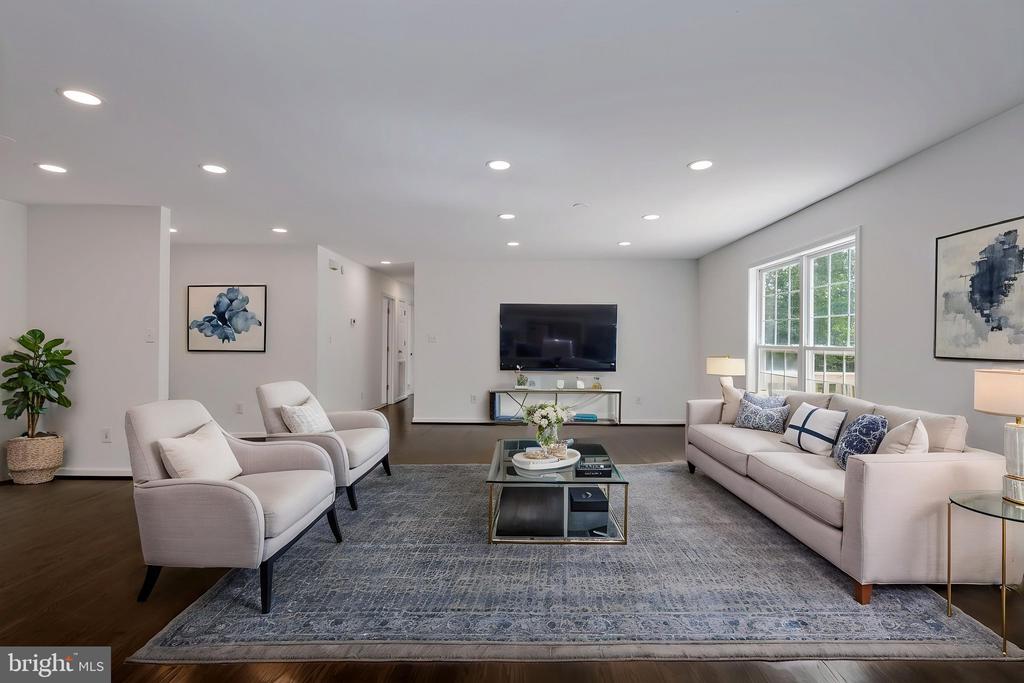 Staged living room with pale seating, a glass coffee table, and a wall-mounted television.