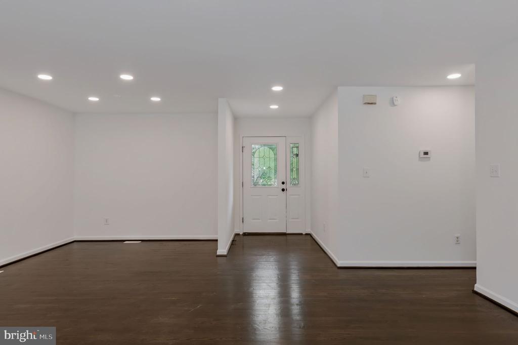 Vacant living room with dark wood floors and a front door with decorative glass panels.