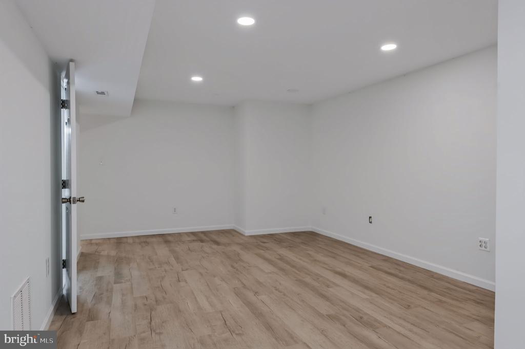 Vacant finished room with light wood-look flooring and recessed ceiling lights.