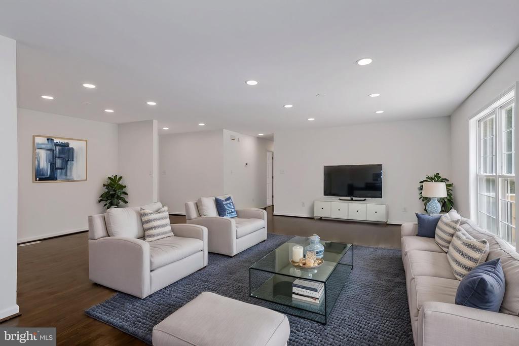 Staged living room with white sofas, a glass coffee table, and large windows.