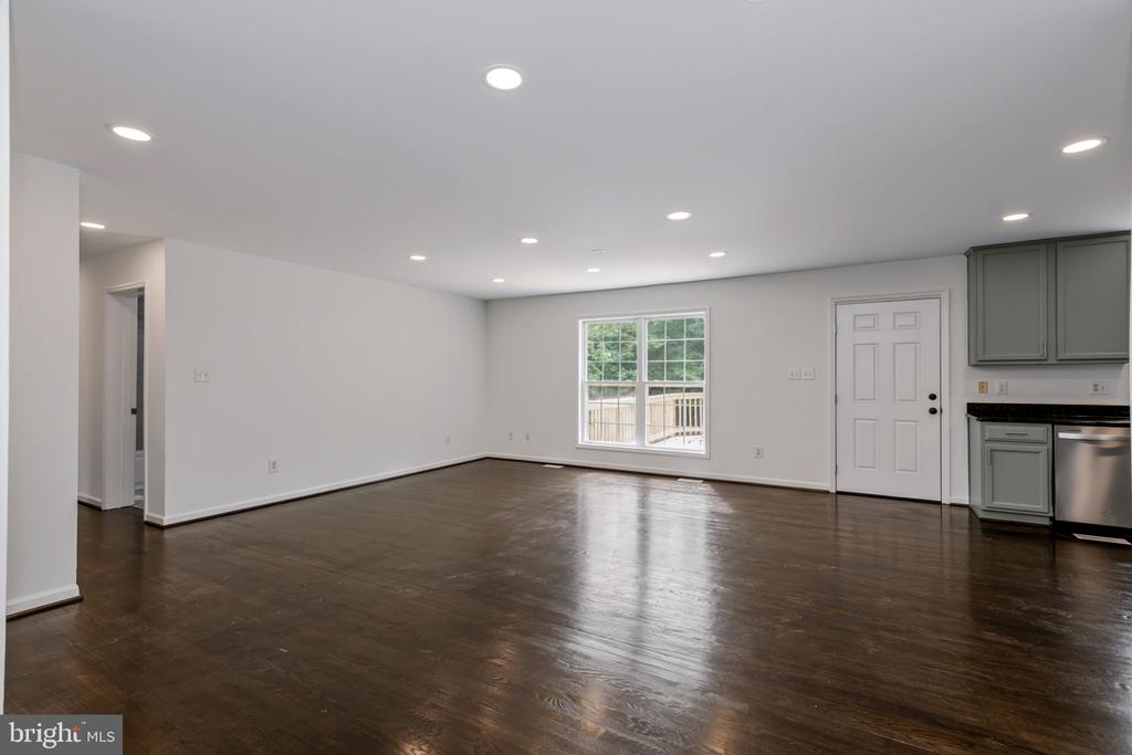 Vacant open living area with dark wood floors, a large window, and gray kitchen cabinets.