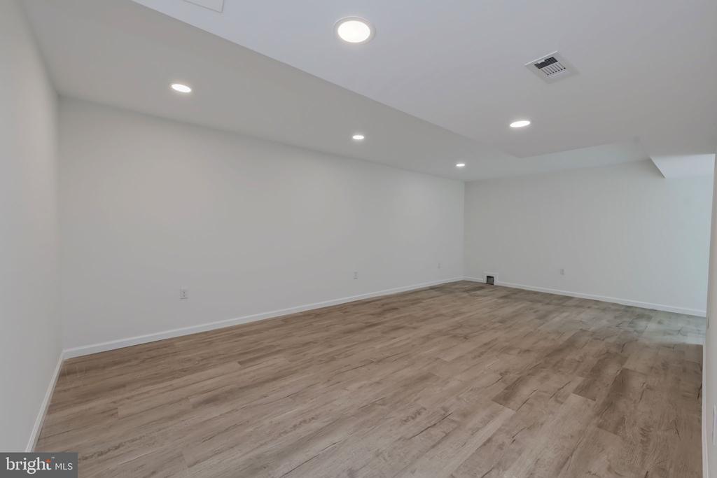 Empty room with light wood-look flooring and recessed ceiling lights.