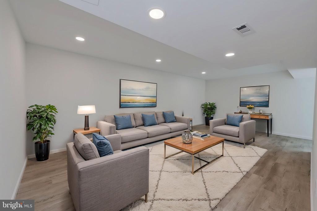 Staged living room with gray seating, blue pillows, a wood coffee table, and coastal artwork.