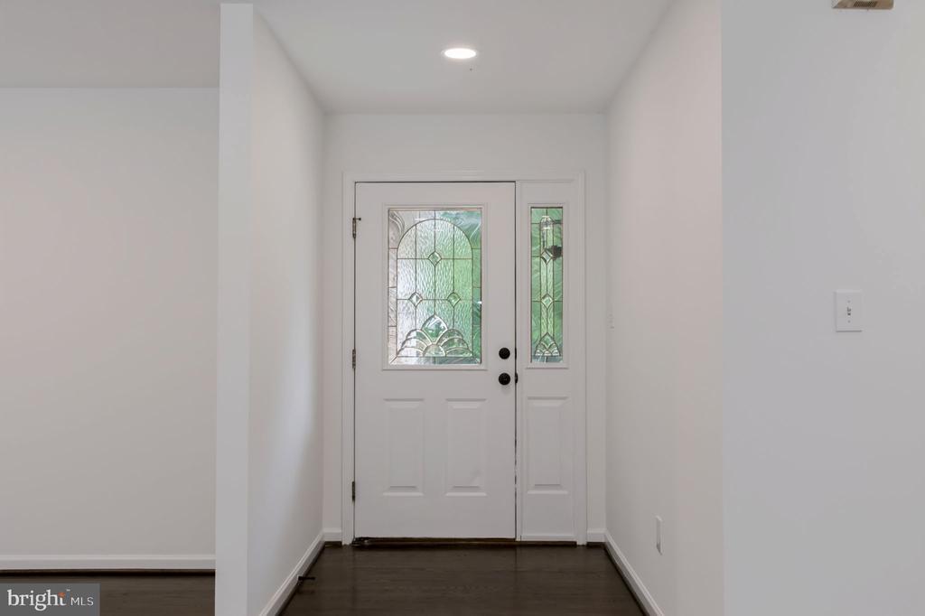 Entry foyer with a white stained-glass front door and dark wood flooring.