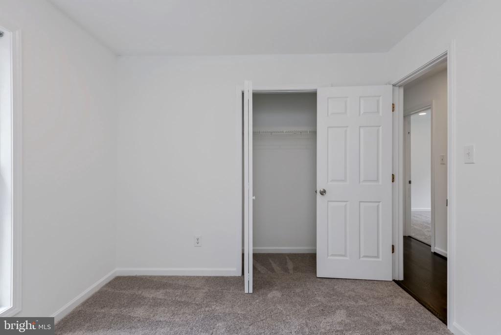 Empty bedroom with gray carpet, an open closet, and a doorway to the hall.