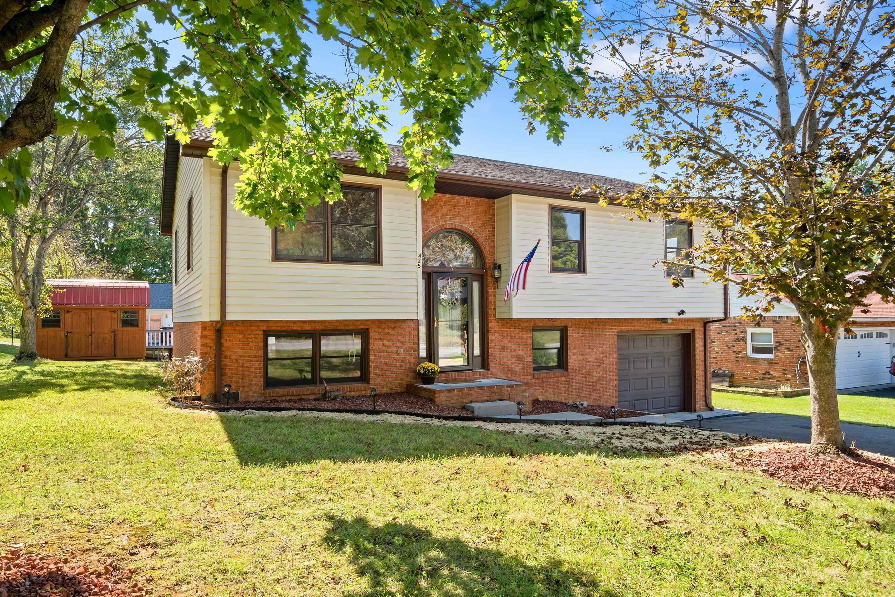 Two-story brick and siding home with an arched entry, attached garage, and American flag.