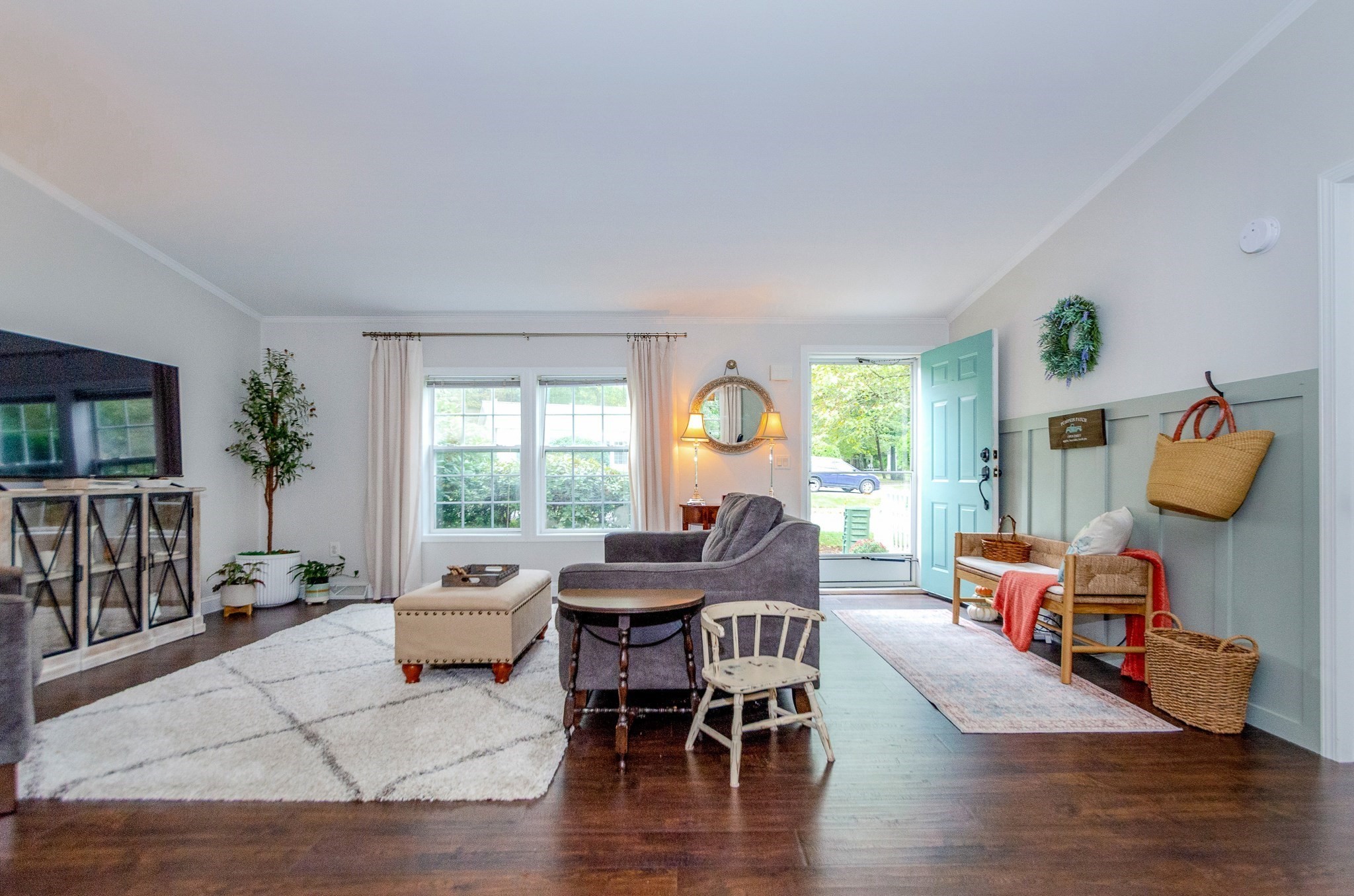 Furnished living room with gray seating, dark hardwood floors, and an open turquoise front door.