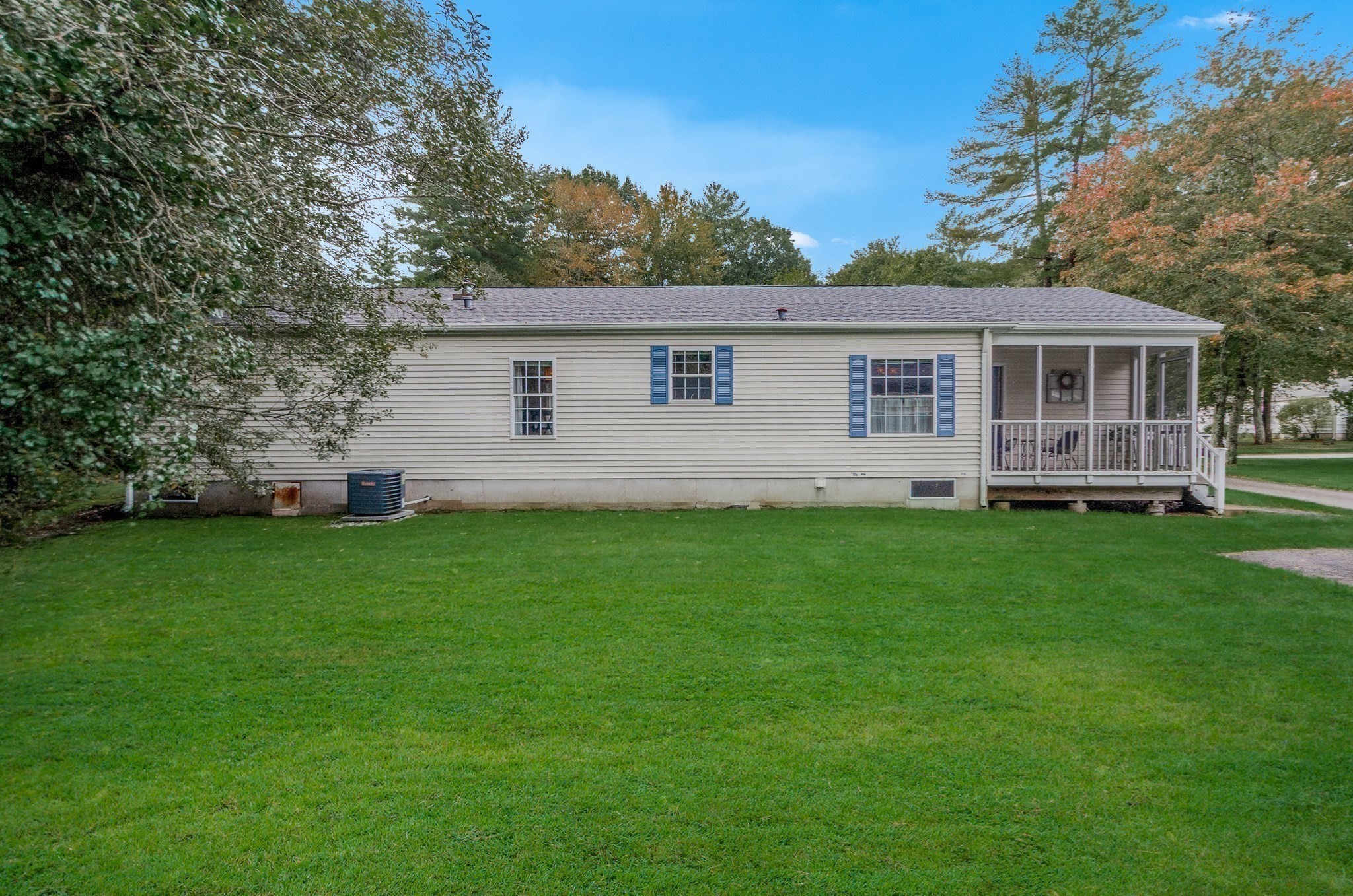Single-story home with a screened porch, blue shutters, and a broad lawn.