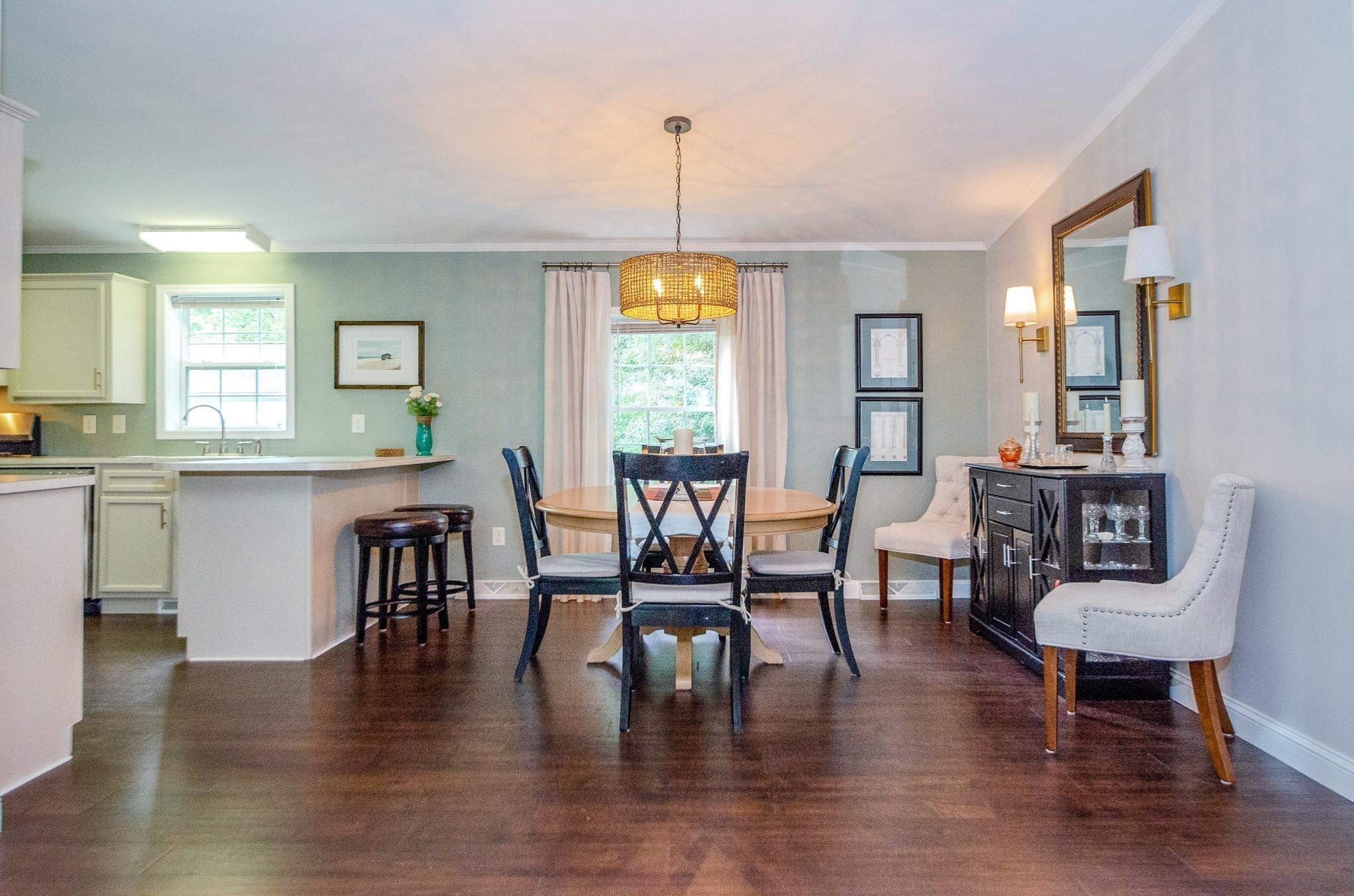 Dining area with a round table, chandelier, breakfast bar, and dark wood floors.