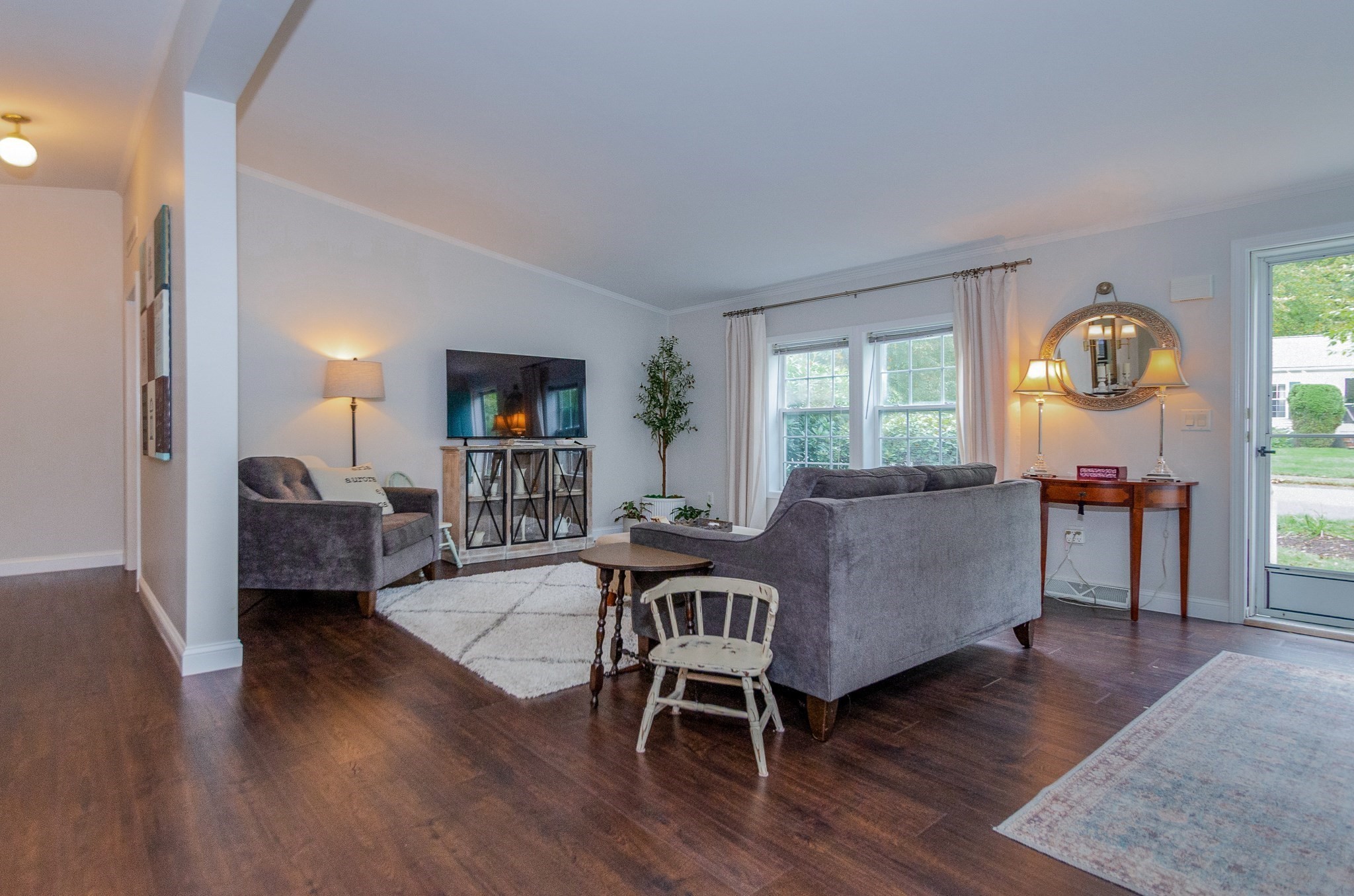 Furnished living room with gray sofas, dark wood floors, and glass doors to the yard.