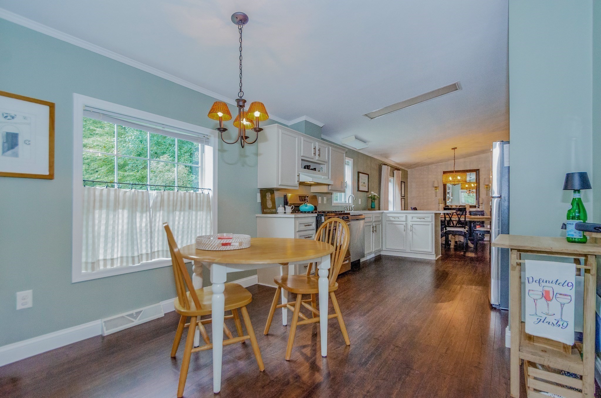 Furnished kitchen and dining area with white cabinets, a round table, and dark wood floors.