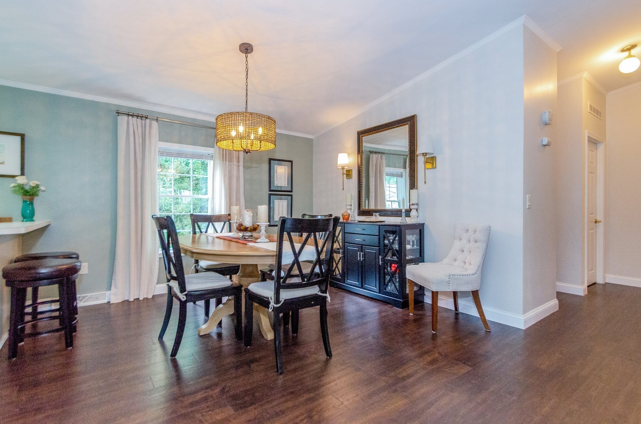 Dining room with an oval table, dark cross-back chairs, blue sideboard, and large mirror.