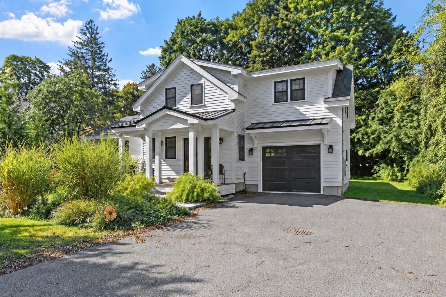 White two-story house with a covered porch, attached garage, and landscaped front garden.