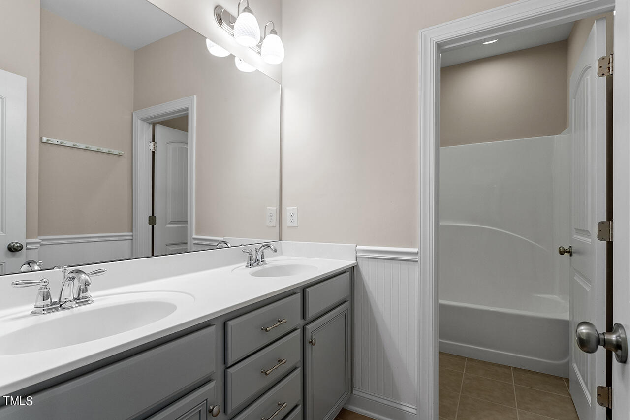 Bathroom with a double-sink gray vanity and an adjoining tub and shower.