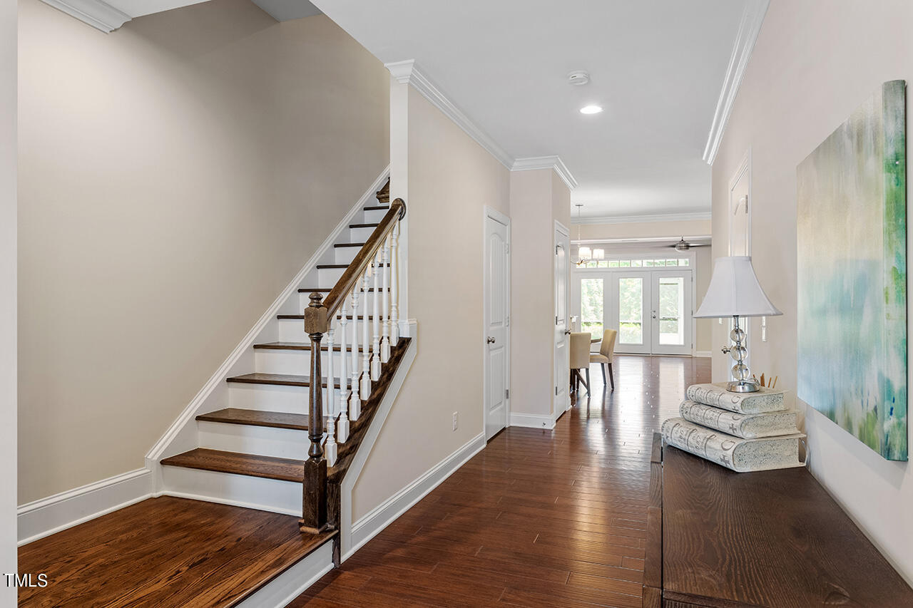 Entry foyer with a dark wood staircase, hardwood floors, and a console table leading to a bright dining area.
