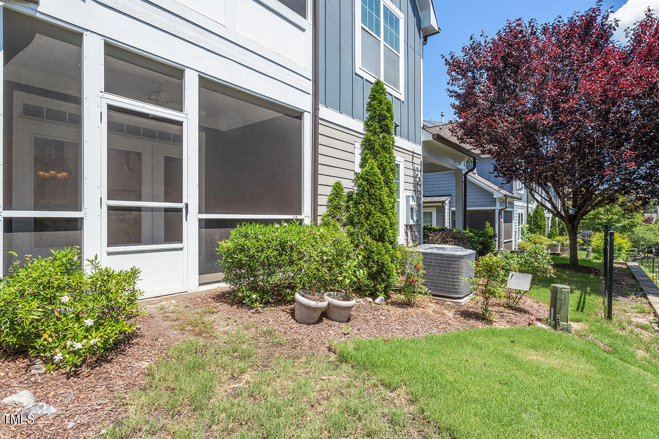 Townhouse exterior with a screened porch, landscaped yard, and mature red-leaf tree.