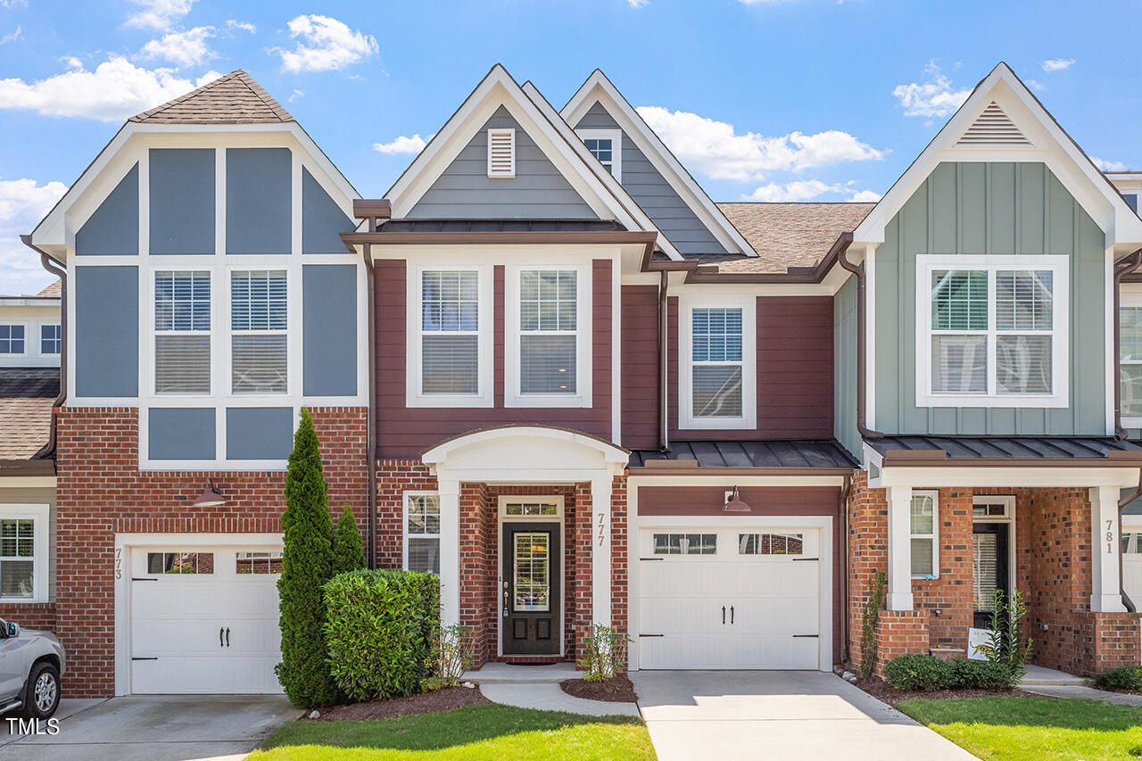 Townhouse exterior with red brick, gray siding, white trim, and an attached garage.