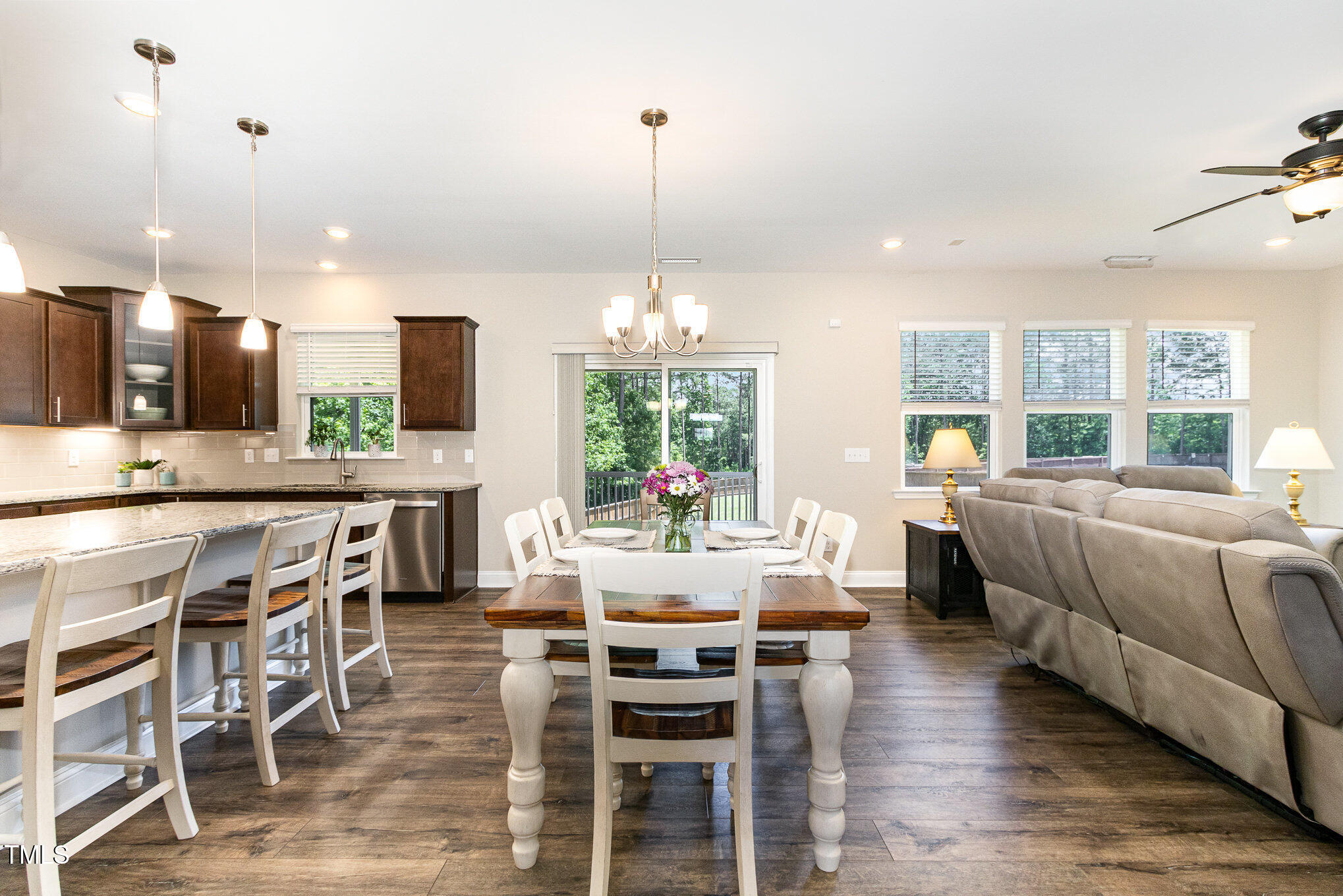 Open-plan kitchen, dining area, and living room with a stone island and deck views.