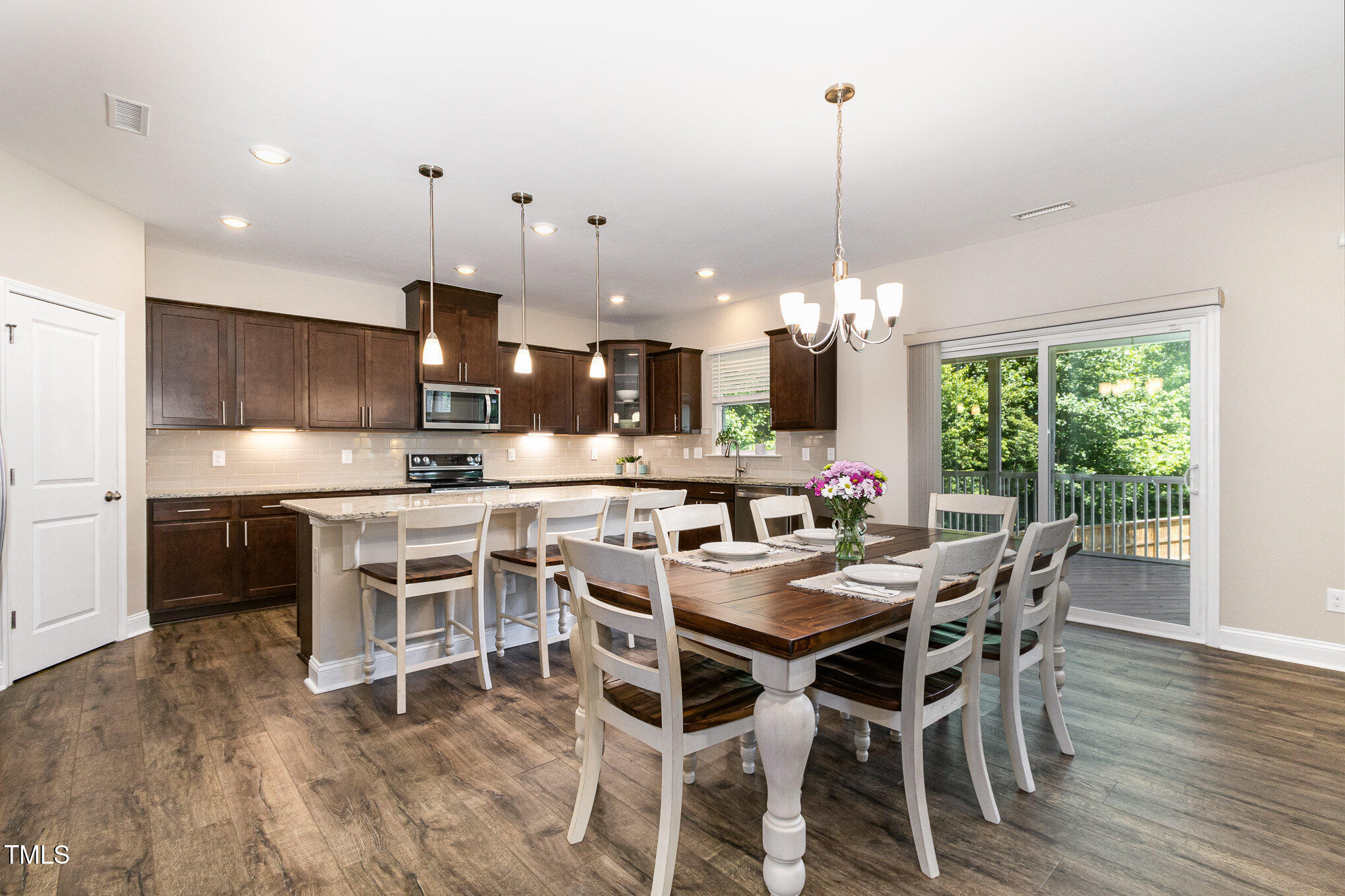 Kitchen and dining area with a large island, dark cabinets, and sliding doors to a deck.
