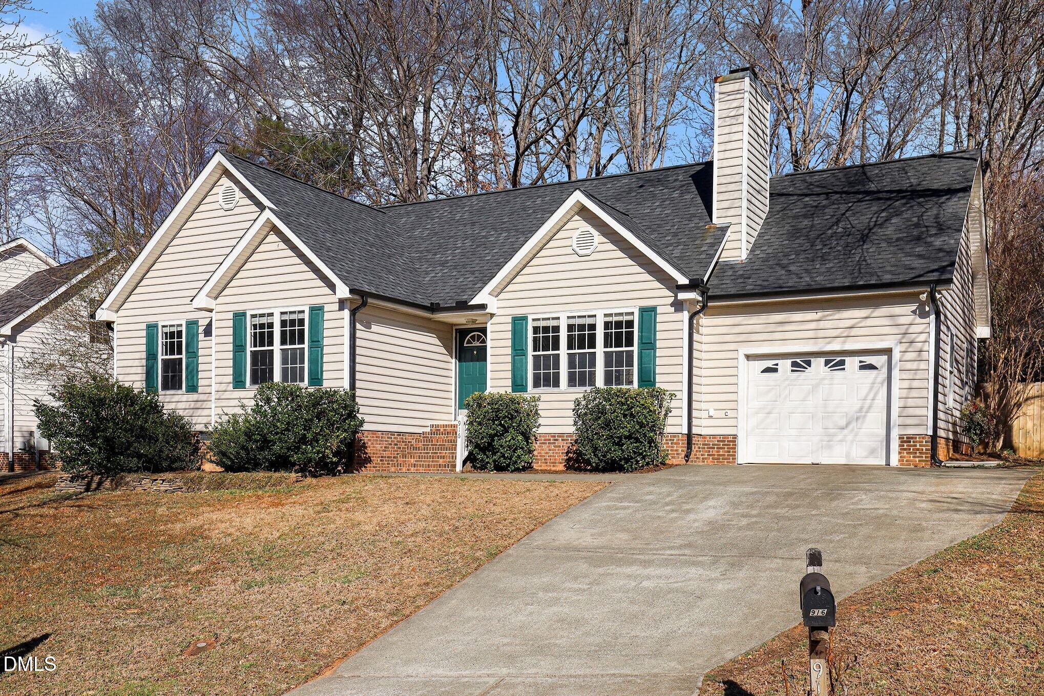 Beige single-story house with teal shutters, brick foundation, attached garage, and driveway leading to mailbox 916.