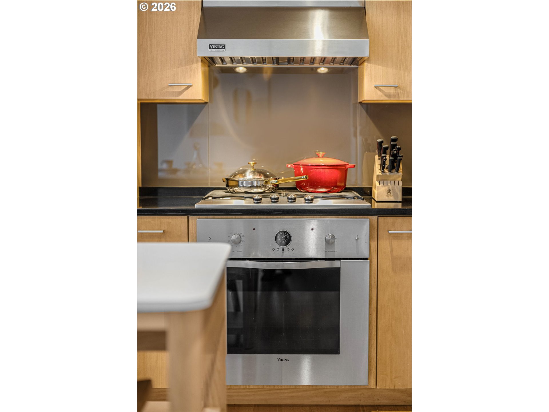 Kitchen cooktop with a red pot beneath a stainless steel range hood.