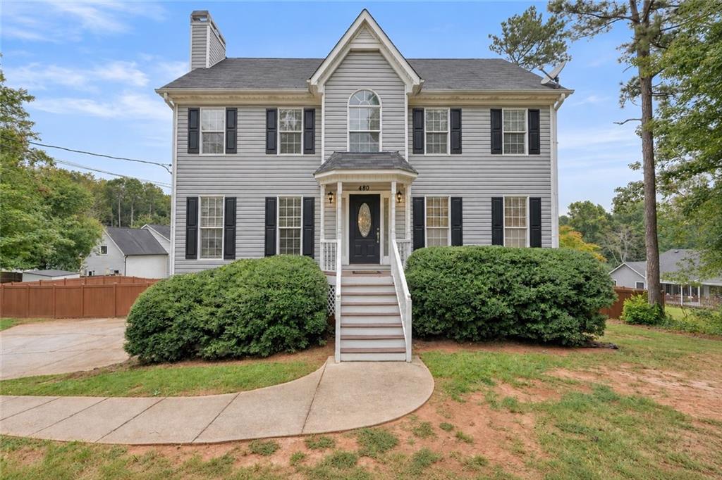Two-story gray house with black shutters, a covered entry, and curved walkway.