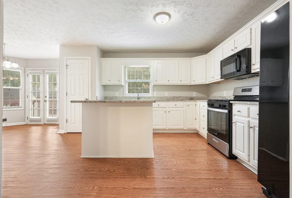 Kitchen with white cabinetry, granite counters, a peninsula, and stainless steel appliances.