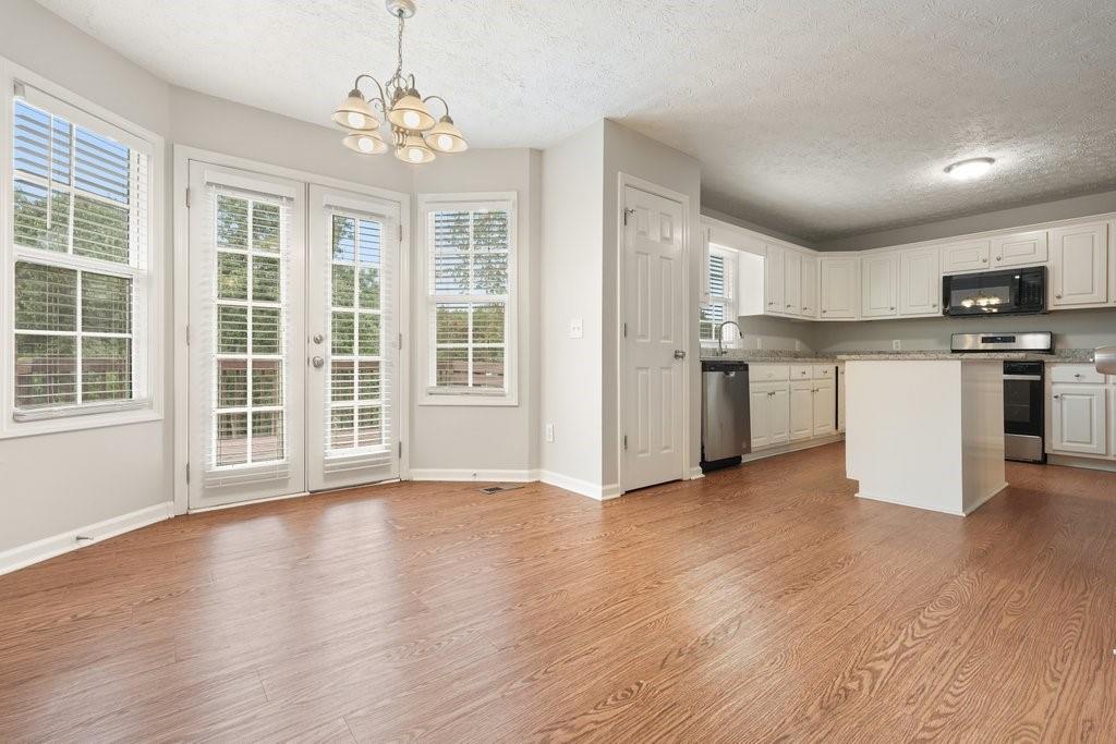 Open dining area and kitchen with a white island, wood floors, and shuttered glass doors.