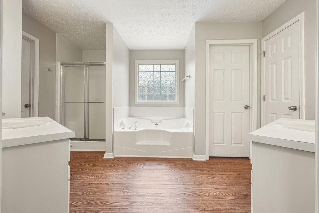 Spacious bathroom with a soaking tub under a glass-block window, separate shower, and vanities on both sides.