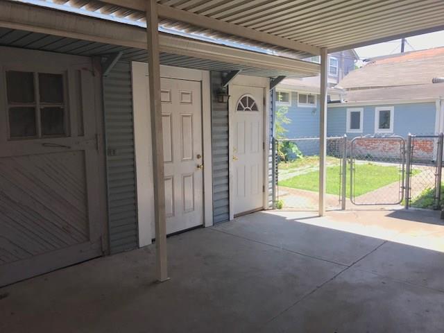 Covered concrete entry with two doors opening toward a fenced yard.